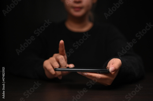 Young woman holding smart phone and touching or pointing to something.