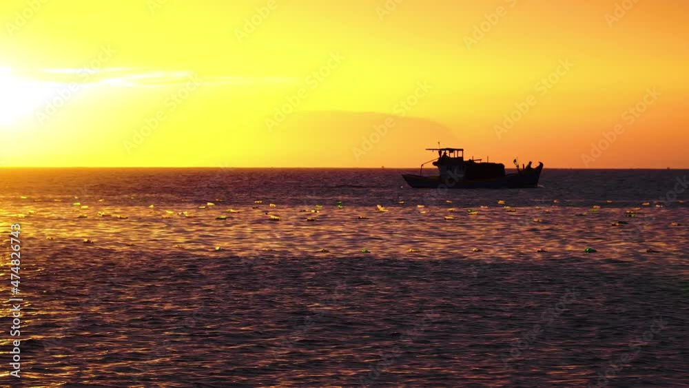 Silhouette of boat passing by ocean water during bright orange golden sunset Silhouette of boat passing by ocean water during bright orange golden sunset