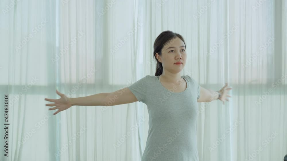 Asian young woman making a stretching - warm up before getting an exercise in a gym Asian young woman making a stretching - warm up before getting an exercise in a gym
