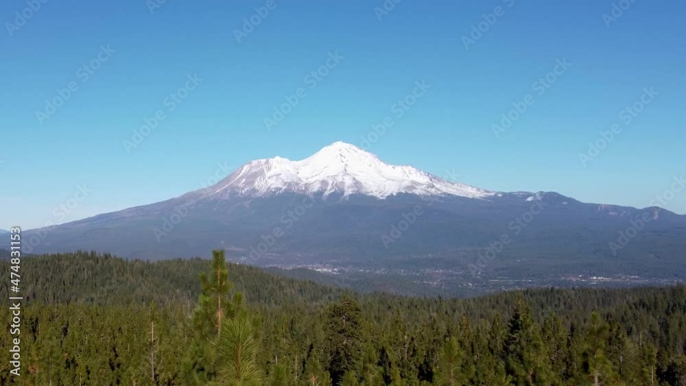 Aerial: Mt. Shasta through the trees. Camera moving through forest towards mountain. Aerial: Mt. Shasta through the trees. Camera moving through forest towards mountain.