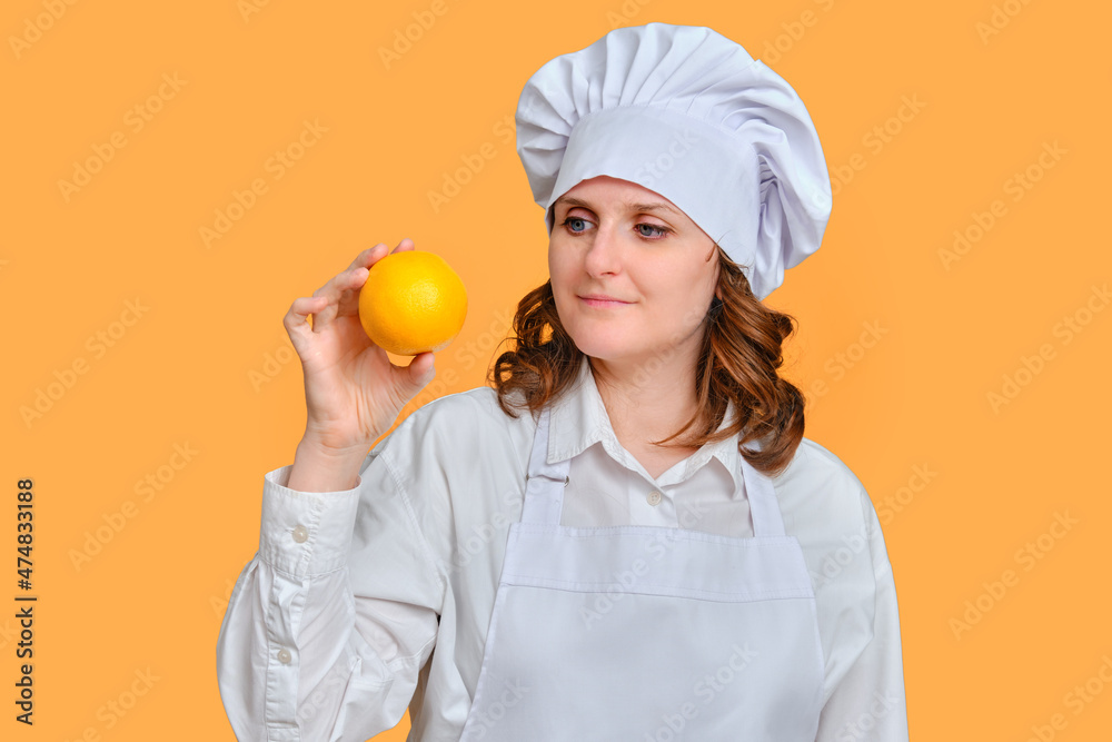 Happy woman chef with orange fruit in hands on studio background, copy space Happy woman chef with orange fruit in hands on studio background, copy space