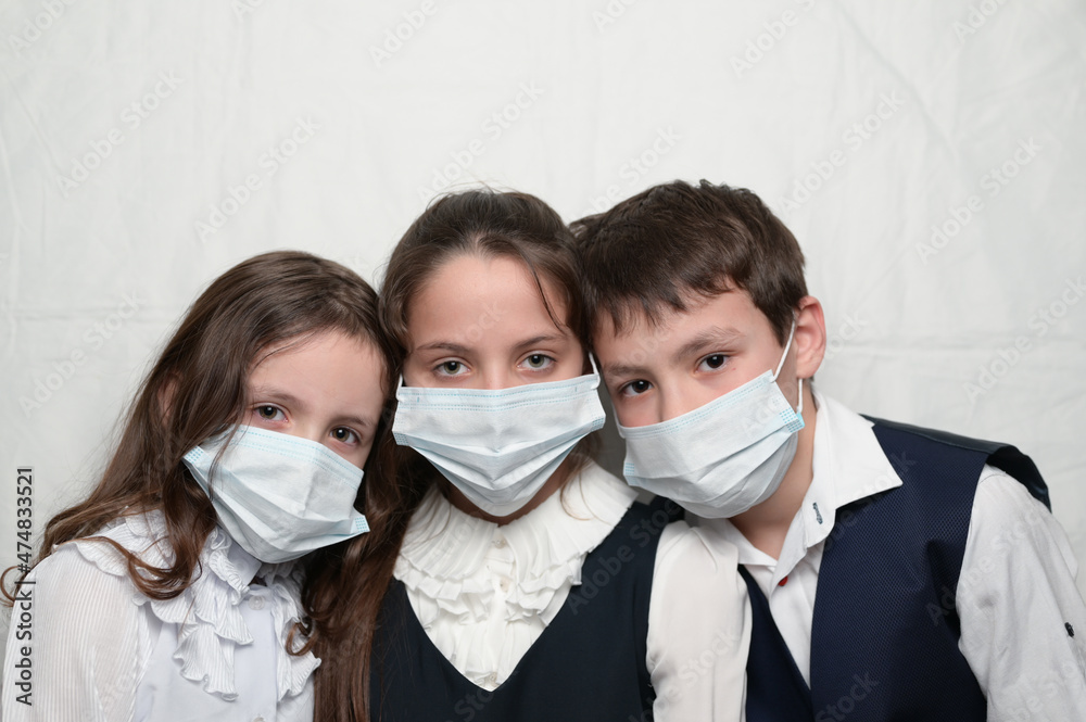 family of three little kids in medical masks and school uniform during coronavirus COVID-19 epidemy quarantine with copy space
