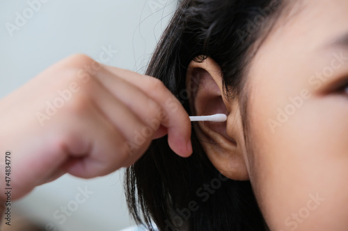 Closeup portrait of person hand putting cotton bud stick inside her ear photo