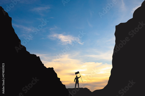 silhouette of a business man holding a victory flag on the mountain