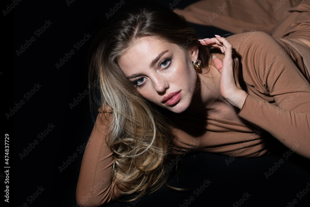 Young woman posing at studio over black background. Sexy girl in sensual seductive pose on black studio. Fashion portrait of beautiful woman with dark light on face. Young woman posing at studio over black background. Sexy girl in sensual seductive pose on black studio. Fashion portrait of beautiful woman with dark light on face.