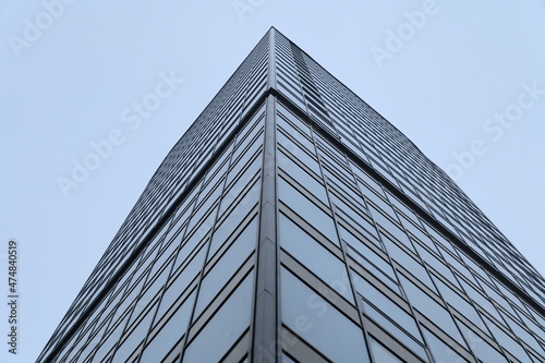 Bottom view of the corner of a high-rise glazed building.