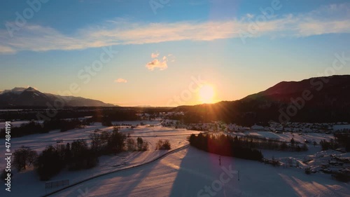 Drone shot of mountains, fields, and landscape in winter at golden hour, sunrise with snow, flying over hills and fields with vibrant colors photo