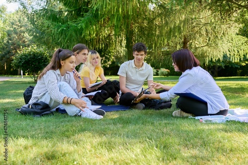 Outdoor, group of students with female teacher sitting on grass