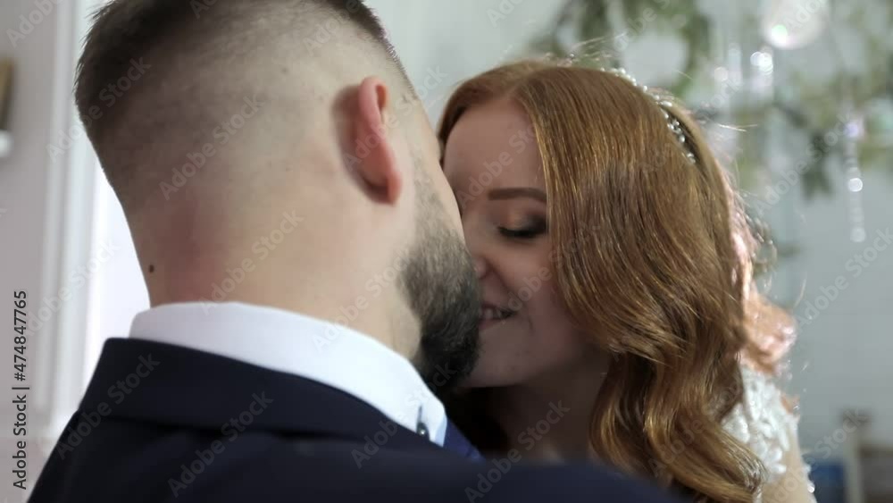 A couple in love kissing at the wedding. The bride in a white dress and the groom in a suit are sitting. A couple in love kissing at the wedding. The bride in a white dress and the groom in a suit are sitting.