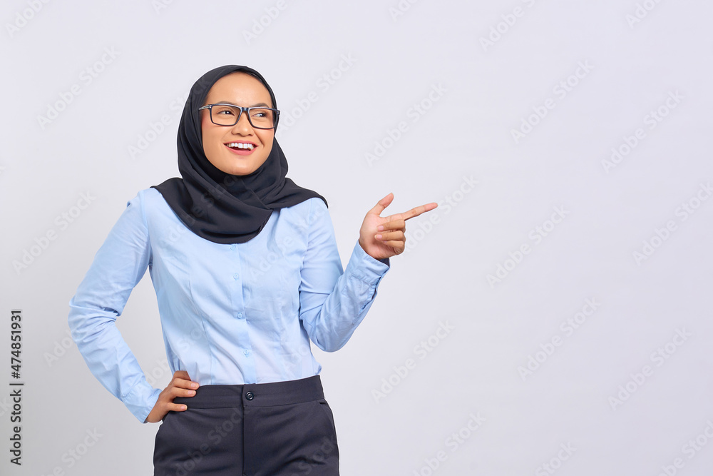Portrait of smiling young Asian woman pointing finger at copy space isolated on white background Portrait of smiling young Asian woman pointing finger at copy space isolated on white background