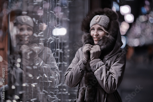 happy girl lights evening christmas shopping standing on the street by the shop window