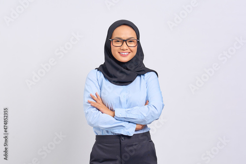 Portrait of smiling young Asian woman standing with crossed arms, looking at camera isolated on white background