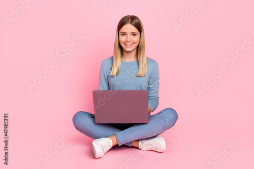 Full body photo of young girl use laptop sit floor homework courses type isolated over pink color background