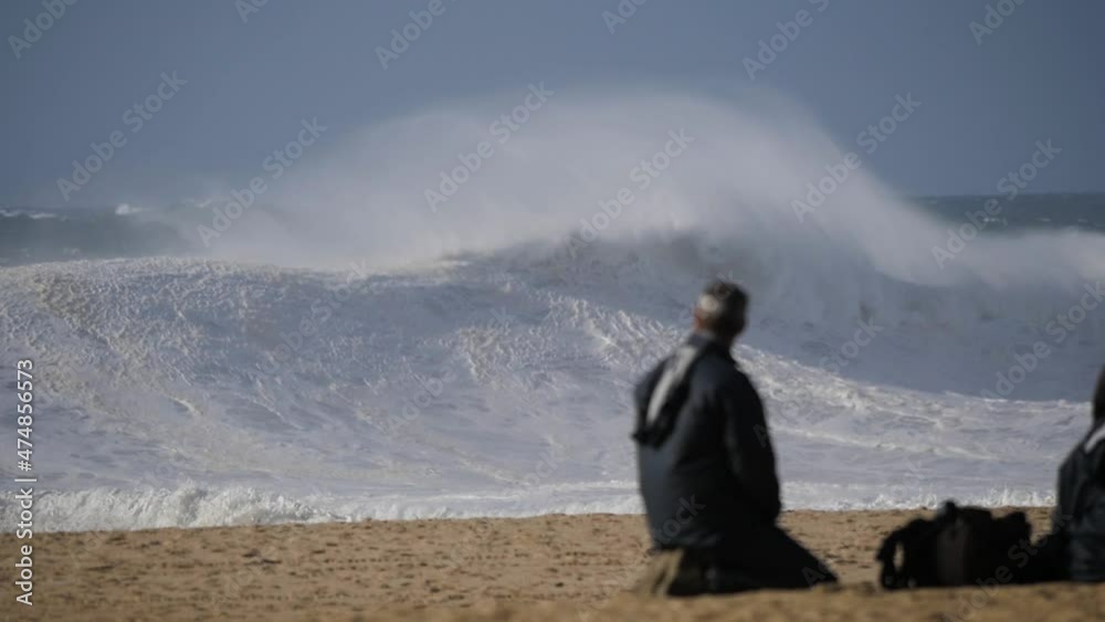 Slow motion of a wave break on the beach in Nazaré, Portugal. Some tourist taking photos at the beach. Slow motion of a wave break on the beach in Nazaré, Portugal. Some tourist taking photos at the beach.