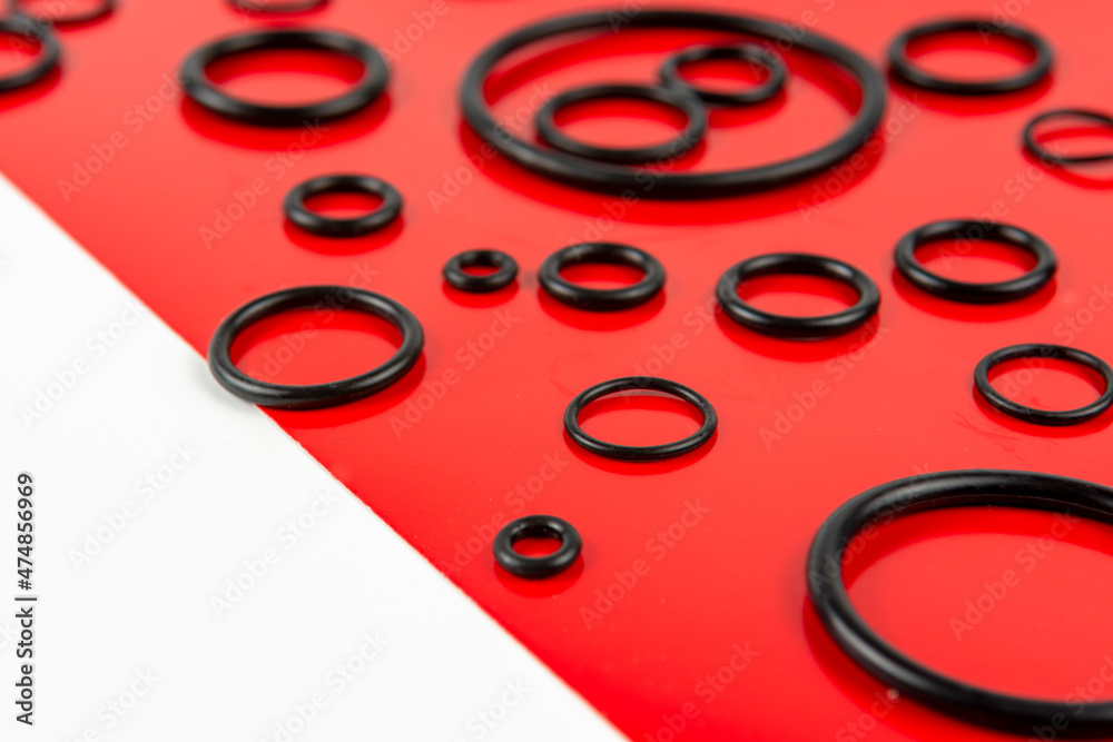 Black hydraulic and pneumatic orings in different sizes on a red and