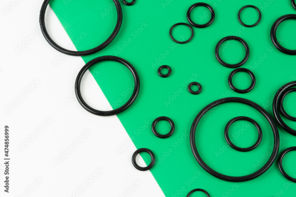 Black hydraulic and pneumatic O-rings in different sizes on a green and white background. Rubber rings. Sealing gaskets for hydraulic connections. Rubber sealing rings for plumbing. View from above Black hydraulic and pneumatic O-rings in different sizes on a green and white background. Rubber rings. Sealing gaskets for hydraulic connections. Rubber sealing rings for plumbing. View from above