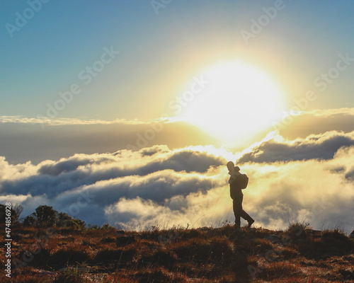 homem caminhando nas montanhas com nuvens ao fundo 