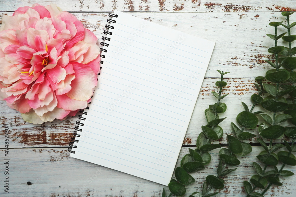 Naklejka premium Notebook with blank pages withh alarm clock and floweron wooden background