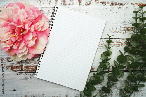 Notebook with blank pages withh alarm clock and floweron wooden background photo