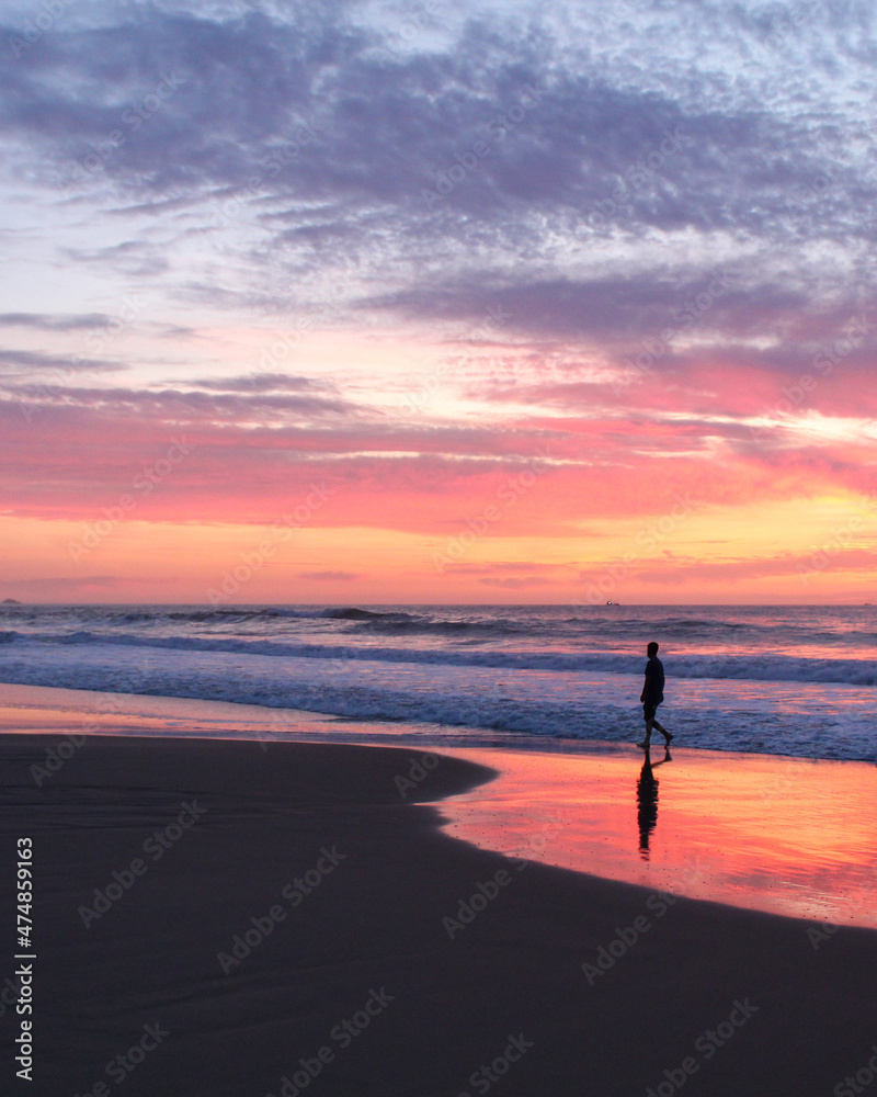pessoa caminhando na beira do mar durante nascer do sol 