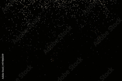 Black festive background of golden glitter lights. Holiday backdrop, selective focus