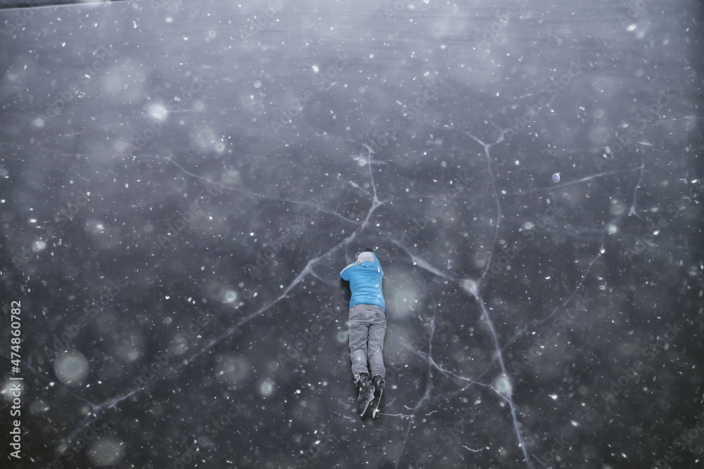 a man in ice skates lies on the transparent ice of the lake, view from above, aerial photography a man in ice skates lies on the transparent ice of the lake, view from above, aerial photography