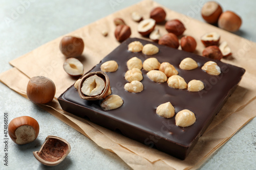 Delicious chocolate bar and hazelnuts on light table