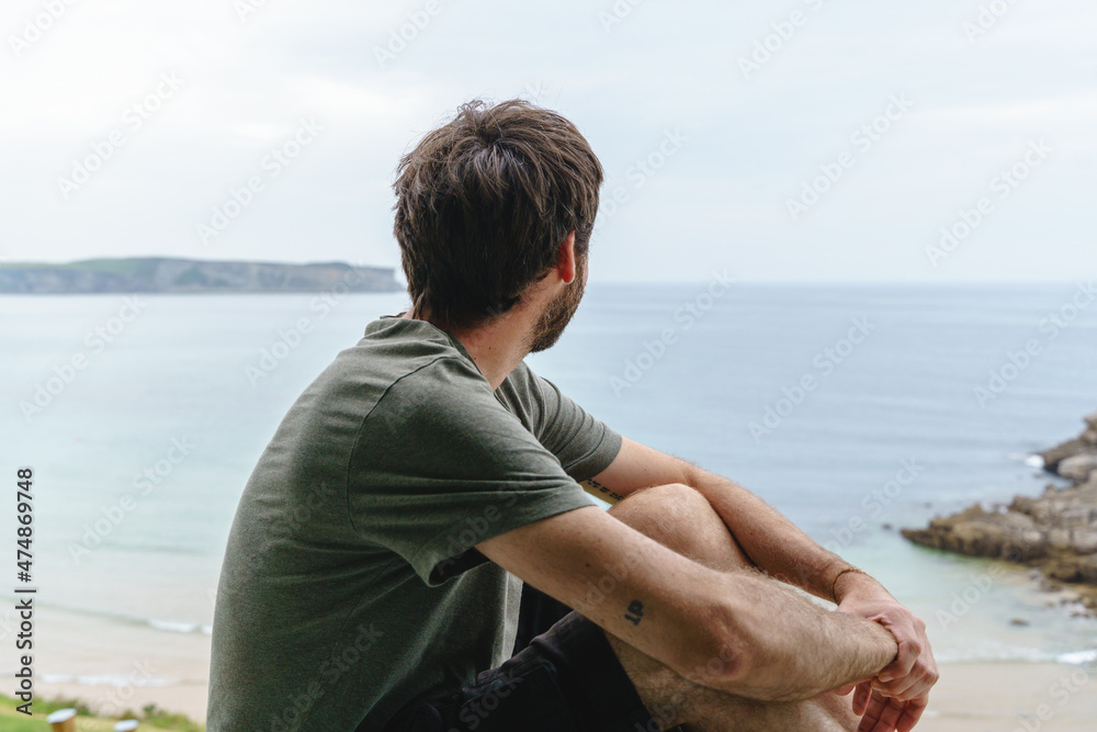 Back view of unrecognizable man sit looking at the sea. Horizontal view of man isolated with a view from the window of the blue ocean on the background. People outdoors Back view of unrecognizable man sit looking at the sea. Horizontal view of man isolated with a view from the window of the blue ocean on the background. People outdoors