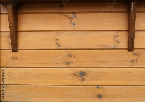a fragment of a light wooden wall with dark details as an empty abstract design background, a backdrop from horizontal textured lacquered boards with knot dots and wood pattern lines