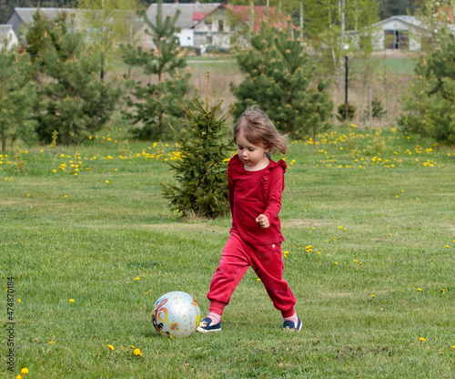 Mała dziewczynka gra w piłkę na zielonej łące