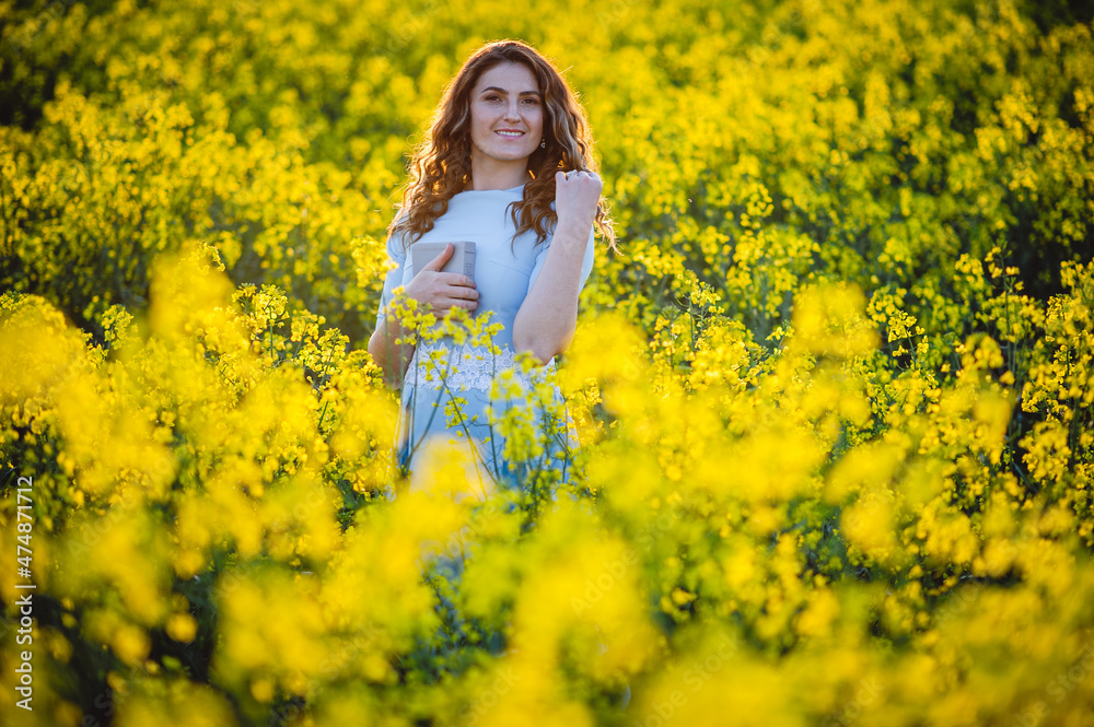 Happy girl hugs the bible in the sunlight on a background of yellow flowers. Girl with a book outdoors. Concept for faith, spirituality and religion. Peace, hope Happy girl hugs the bible in the sunlight on a background of yellow flowers. Girl with a book outdoors. Concept for faith, spirituality and religion. Peace, hope