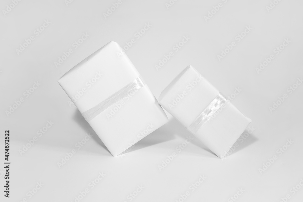 Two gift boxes in white wrapping paper with white rope on white table. Isolated wrapped gift mock up with ribbon. Two gift boxes in white wrapping paper with white rope on white table. Isolated wrapped gift mock up with ribbon.