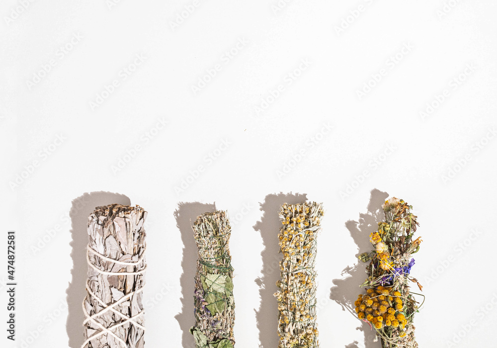 Herbs for spiritual cleansing - white sage and various aromatic herbs bundles on white background
