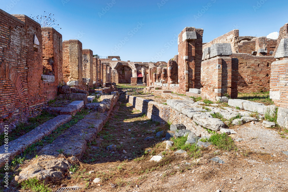Suggestive street view in ancient Roman village with ruins and remains of palaces and ancient luxurious shops with typical architecture and bricks walls