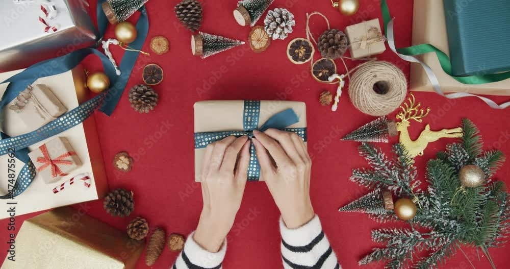 Top view of girl hands unpacking present gift box winter christmas decorations on red background. Minimal creative flat lay of christmas traditional composition and new year holiday season.