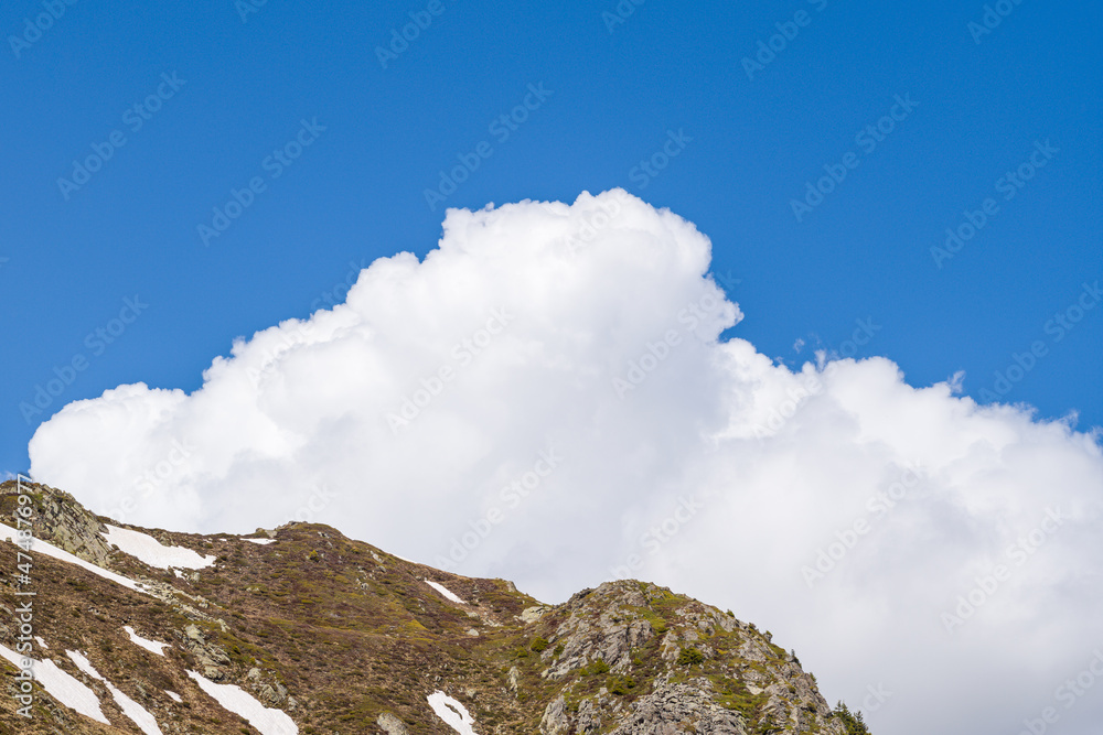 White clouds above the Aiguillette des Houches in the Mont Blanc massif in Europe, France, the Alps, towards Chamonix, in summer, on a sunny day.