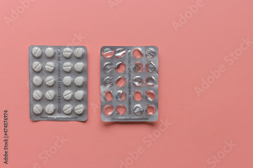 Empty and full blister packs of pills on pink background, supplement and medicine concept. Close-up, top view, frame, copy space