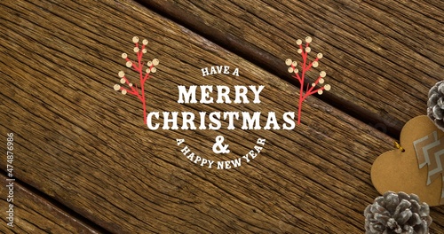 Overhead view of merry christmas and new year greetings on wooden table with pine cones