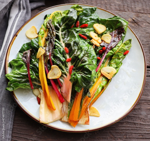 Wilted swiss chard salad with butter and garlic on rustic table photo