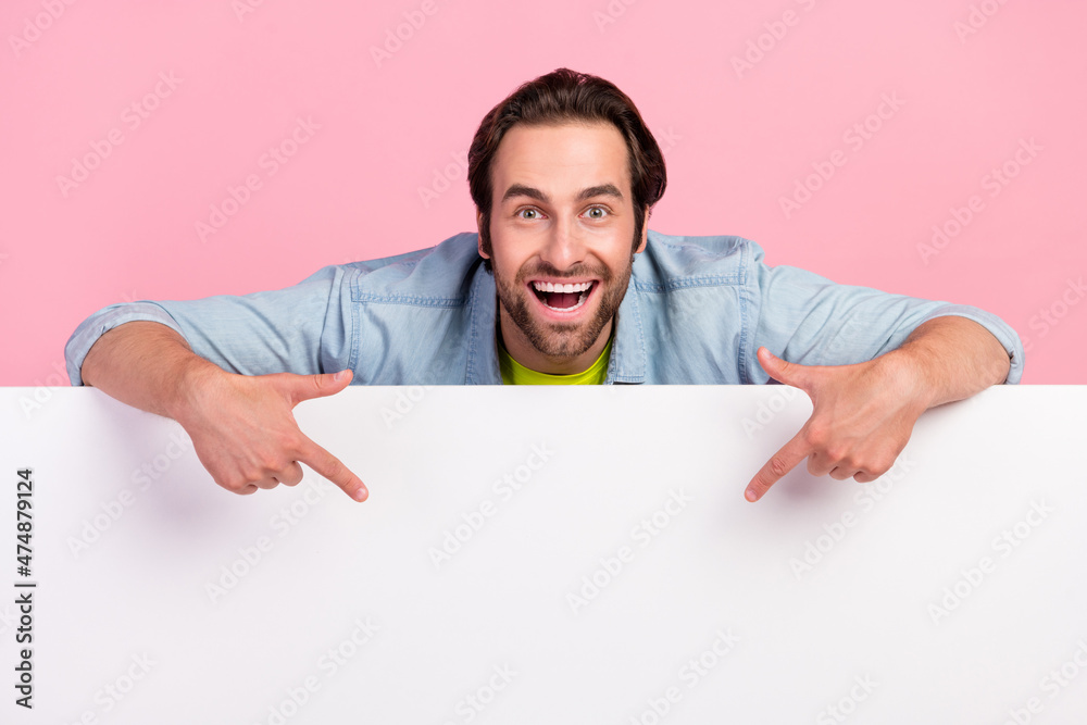 Photo of young excited man indicate fingers empty space ad promo choice isolated over pink color background Photo of young excited man indicate fingers empty space ad promo choice isolated over pink color background