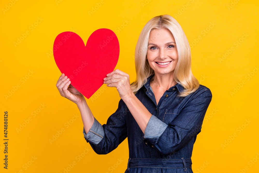 Photo of pretty sweet lady pensioner dressed denim outfit rising big red heart isolated yellow color background