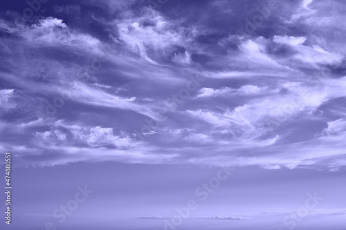 Sky with feather clouds, violet very peri color, abstract background. photo