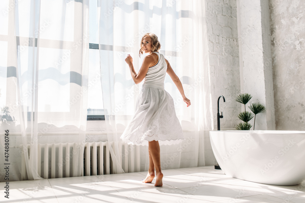 young beautiful girl, with a bright smile, in a large bright room. the room is filled with sunlight, the girl is wearing light clothes. young beautiful girl, with a bright smile, in a large bright room. the room is filled with sunlight, the girl is wearing light clothes.