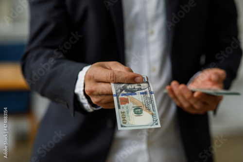 Businessman Hand holding US dollars, American bills money dollars in hand. Saving money and investing or Bribery and corruption concept.
