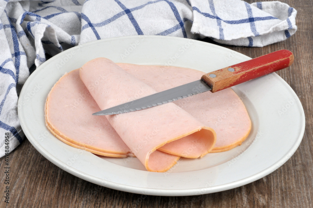 Tranches de jambon blanc dans une assiette avec un couteau posée sur
