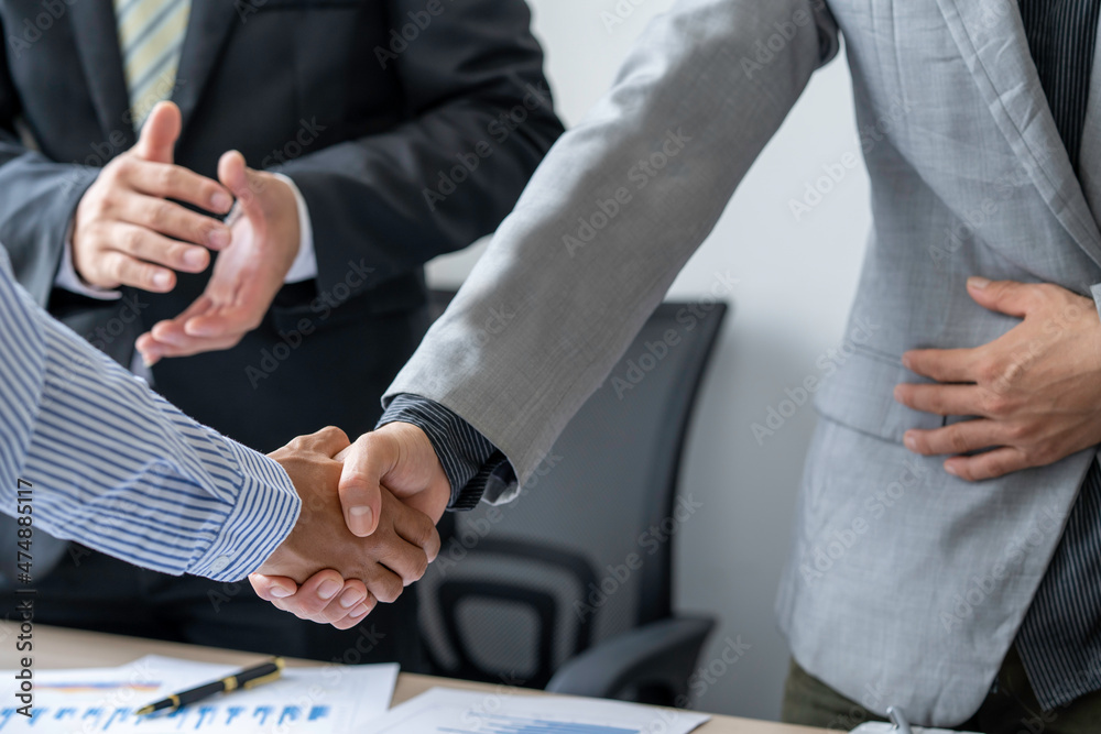 Obraz premium businesspeople are shaking their hands after signing a contract at the meeting, close-up. Business communication concept