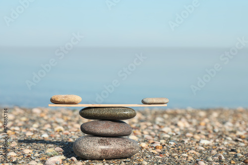 Stack of stones with wooden stick on beach  space for text. Harmony and balance concept