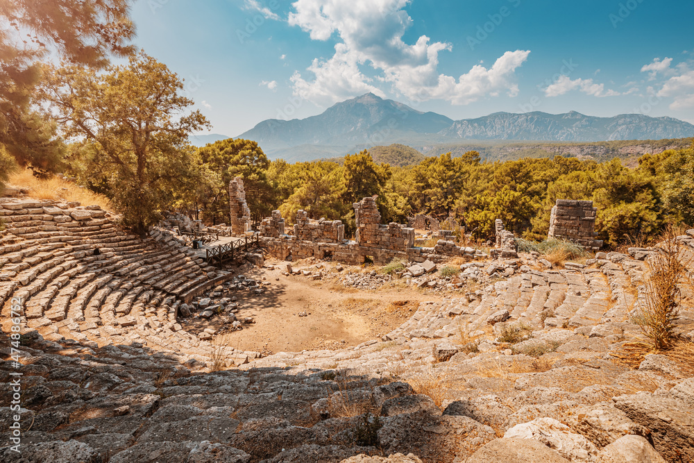 Ruins of an antique Greek amphitheater in the ancient city of Phaselis in present-day Turkey with Tahtali mountains in the background. Sightseeing and travel