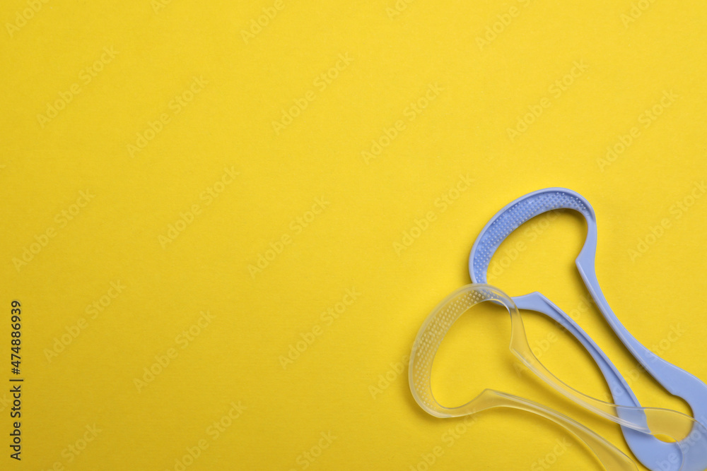 Naklejka premium Tongue cleaners on yellow background, flat lay. Space for text