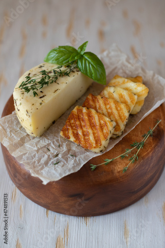 Slices of fried halloumi cheese with a beautiful grilling pattern rests on a wooden tray.